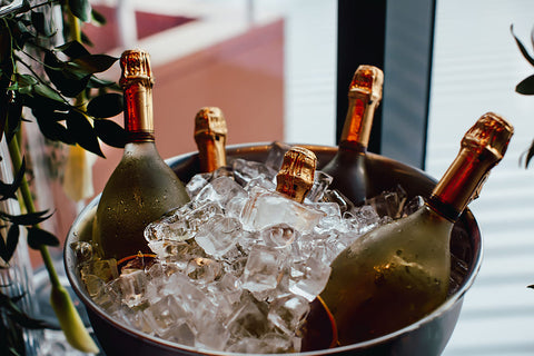 wine serving temperature: 5 bottles of wine chilling in ice bucket