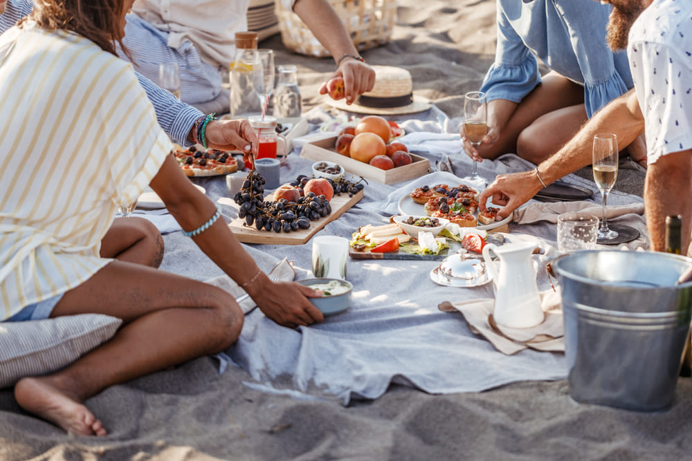 group of friends having a wine picnic at the beach